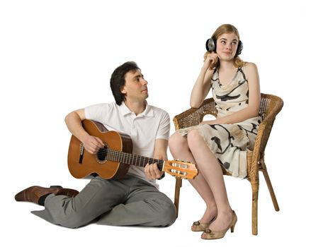 A woman in headphones and a man playing guitar for her