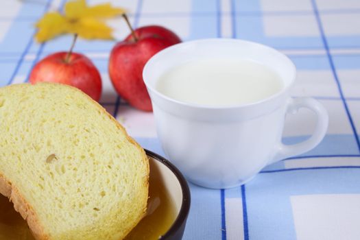 Cup of milk with a cornbread and honey removed close up