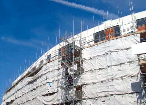 A general view of the exterior of a new modern building site development covered in scaffolding and cladding.