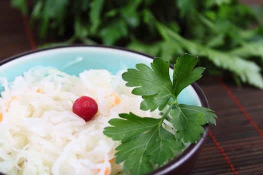 Salad from salty cabbage with a cowberry on a bamboo napkin removed close up