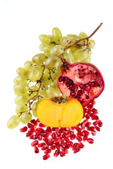 Grapes, a pomegranate and a persimmon removed close up on a white background without isolation