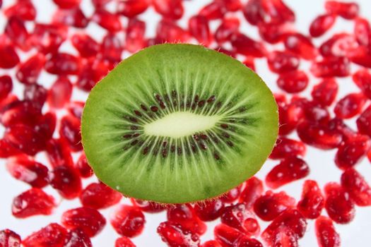 The cut fruit kiwi against garnet grains removed close up