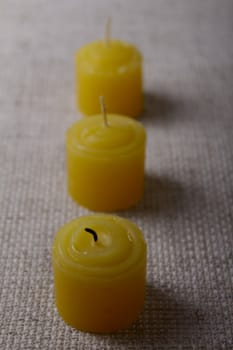 Three tea candles on a linen napkin removed close up