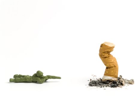 A toy soldier aiming to a cigarette butt.