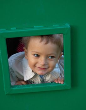 Happy childhood. Little boy at playground looking through little window