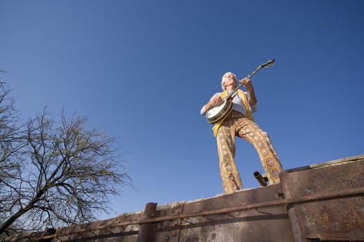 Wide angle shot of a banjo player against the blue sky