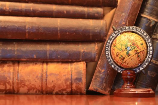 Vintage still life with stack of old books and globe on wooden table