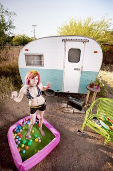 Colorful young woman flexing in a play pool