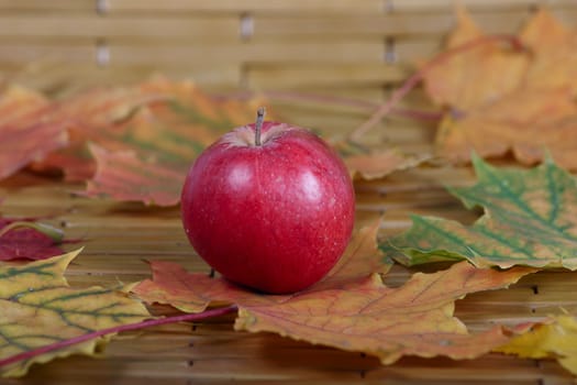 The red apple which has been removed on a bamboo napkin in an environment of autumn leaves