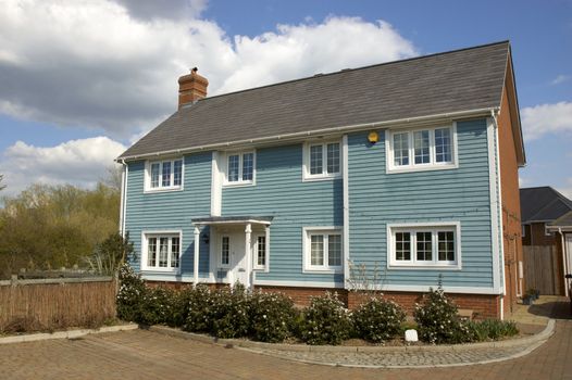 A blue wooden clad house with a cloudy sky