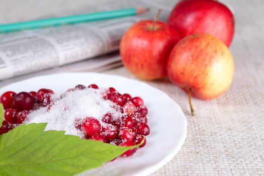 Plate of a cowberry sprinkled with sugar removed close up against a linen napkin