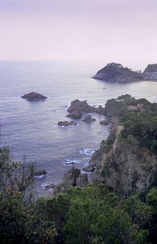 A purple sunset falls over the rocky cliffs of the Costa Brava.