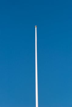 Empty flagpole against deep blue sky.
