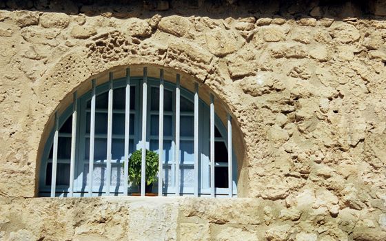 A rounded window in the traditional Provencial blue colour, on a stone house, Les Baux de Provence, France.