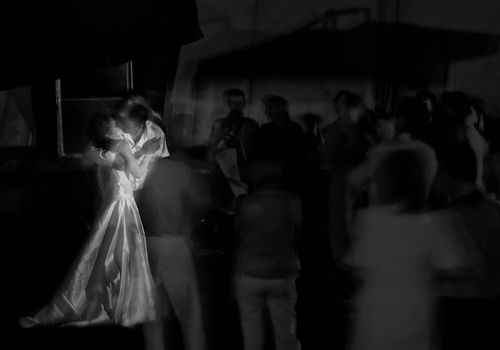 Kissing newlywed in a round of guests. Long exposure shot, focus on bridge, peoples blurred. Black and White shot