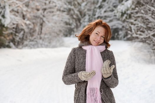 Happy red-haired woman having fun on winters day in forest.