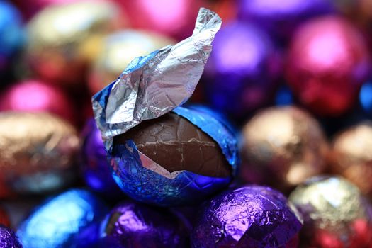 A chiocolate easter egg in a blue wrapping on a background of chocolate easter eggs