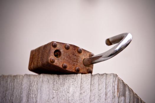 An open weathered lock in macro shot on top of a wooden fence