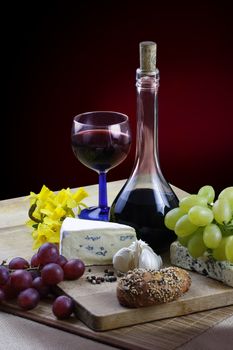 Romantic dinner with cheese, wine, grapes and jonquils on rustic board