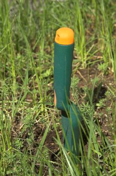 A green gardening spade, stuck into an umkempt flower bed
