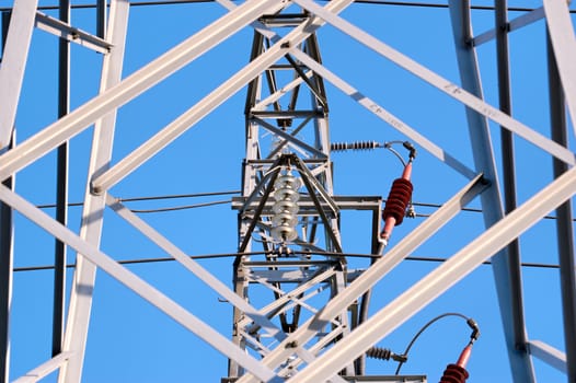 A power line fixture, seen through a rhombic opening of a nearby mast
