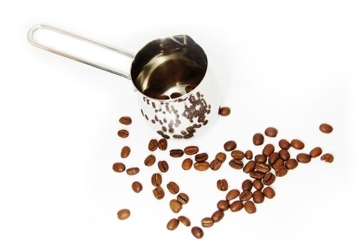 Metallic ibrik with reflected coffee beans and ground coffee