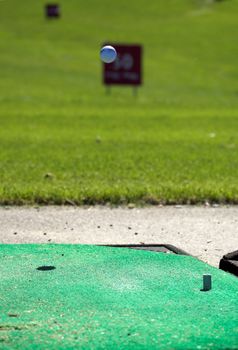 A golfball, flying from the shooting location on a golf training range
