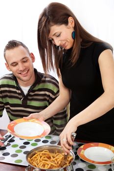 Young, happy couple at dinner. The wife fills her plate