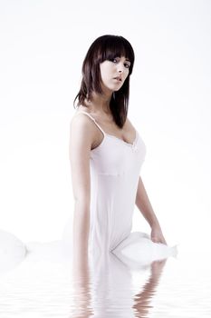 Cute brunette flirting in bed dressed in a white nightgown