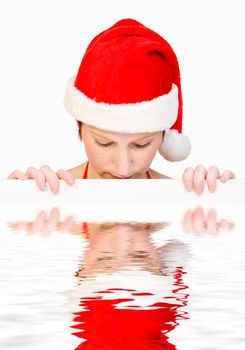 Beautiful girl in christmas bikini and with christmas hat is holding up a white sign for copy space. With background clipping path for your convenience