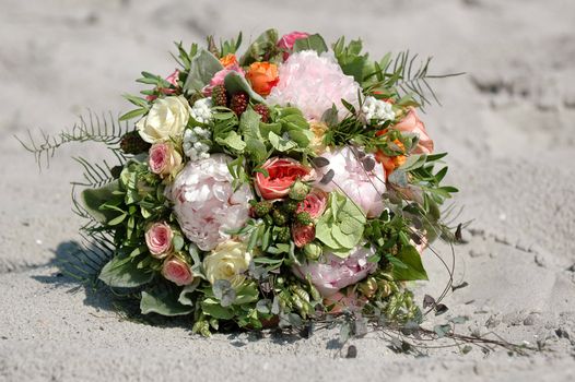 Wedding flower bouquet. The flowers are lying in the sand.
