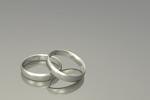 Silver wedding bands on a grey background.