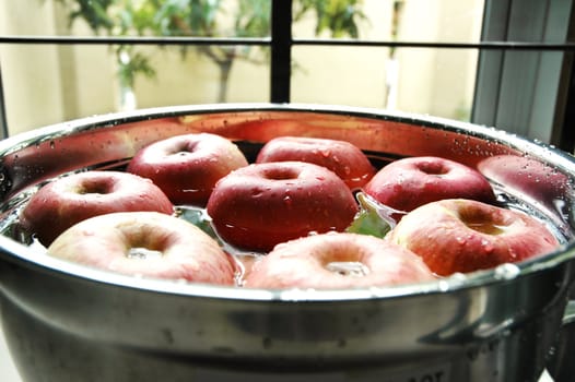 Fresh red apples floating on water beside kitchen window