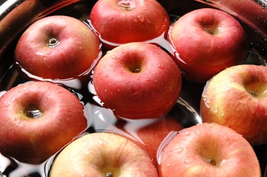 Fresh red apples floating on water in container