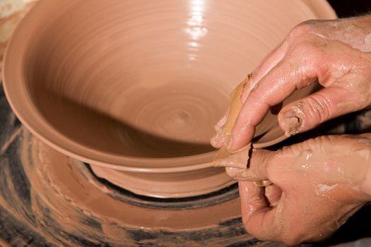 Closeup on hands of potter shaping clay on wheel