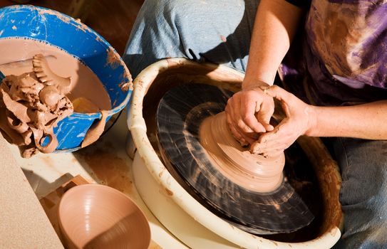 Potter shaping wedge of clay on spinning wheel