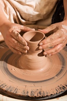 Closeup on hands of potter shaping clay on wheel