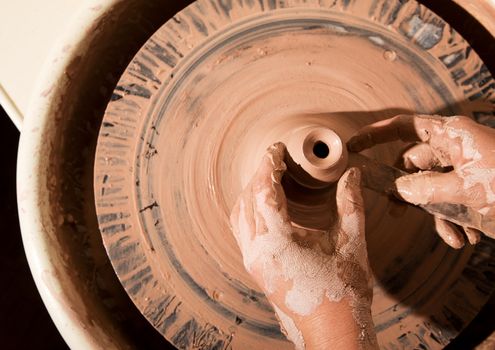 Overhead shot of potters hands with file shaping vase