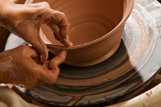 Closeup on hands of potter shaping clay on wheel