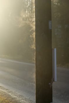 A streetlamp pole, frozen during the night, steams in the early morning sun.
