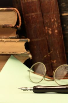 Vintage still life with old fountain pen on background with paper sheet and books