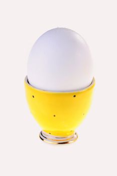 Egg in a yellow support for eggs on a white background.