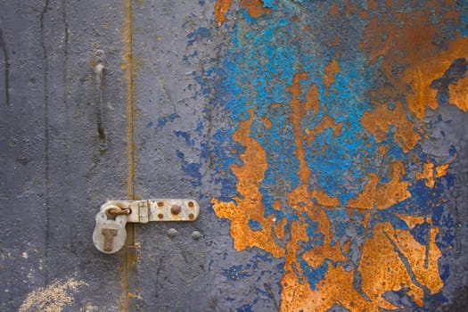 Colorful coroded metal door padlocked shut