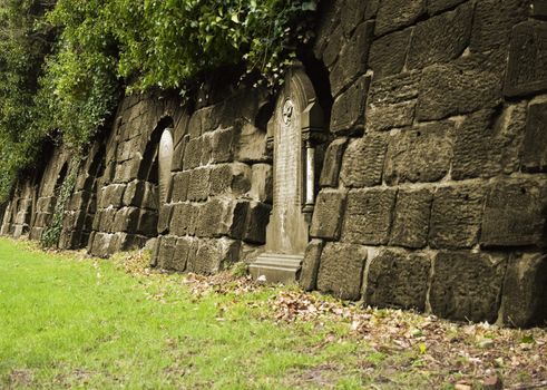 Row of very old tombstones leading into a tunnel