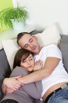 Young couple arm in arm lies sleeping on a sofa