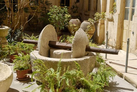 Dual rotating grinding stone - Maltese style. Surrounded by ferns.
