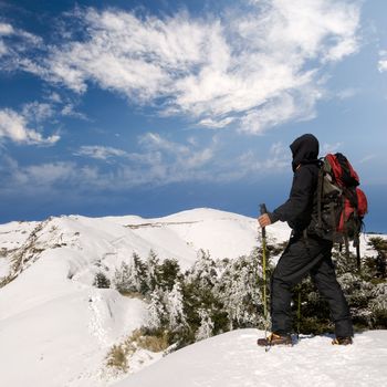 Man walk on snow lane of mountain in winter with dramatic sky and clouds.