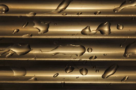 Detail view of water droplets on a stainless steel kitchen sink with interesting brown-golden lightning