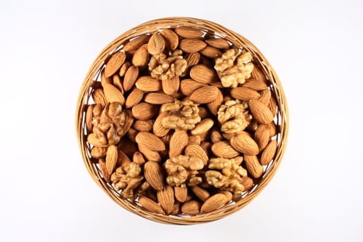 Almond nuts and walnuts in a round basket, top view