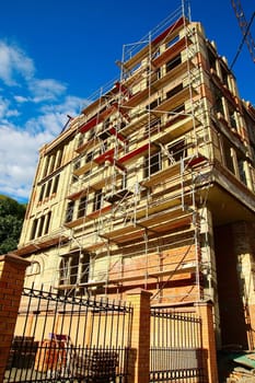 Brick building with falsework under construction against blue sky